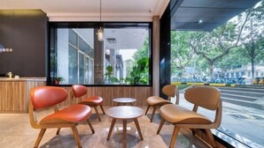 A modern interior with a reception desk, seating area with chairs and tables, large windows offering a view of the street and greenery outside. - HanTing Hotel (Jiaxing Nanhu Yaohan Shopping Mall Area) (Jiaxing)
