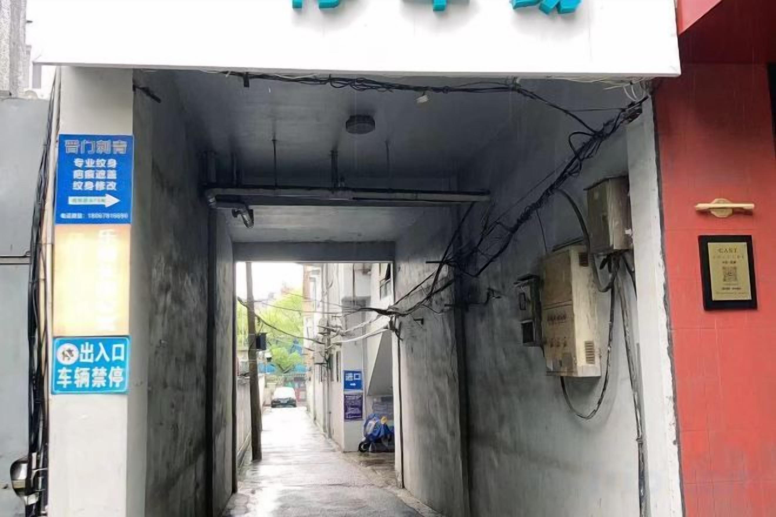 A narrow alleyway with a sign indicating a parking area and a direction to a specific location.