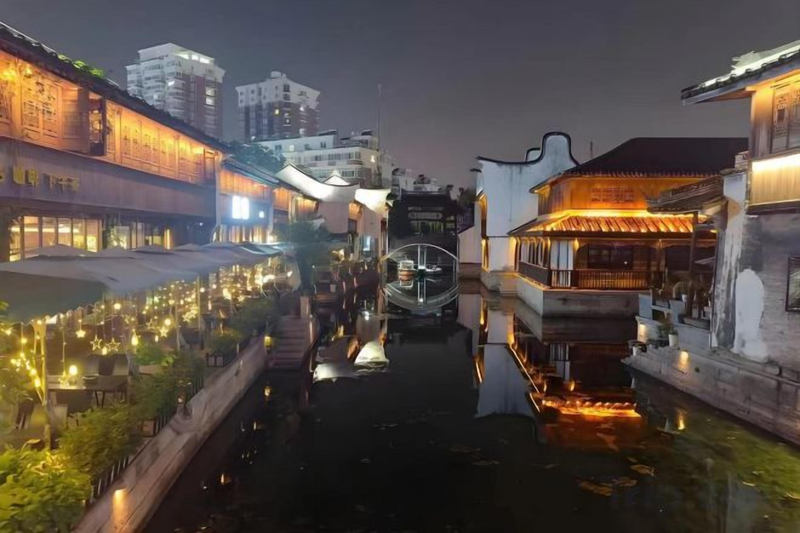 Ein Kanal mit Gebäuden an beiden Ufern, ein Boot im Wasser und Lichter, die sich auf der Oberfläche spiegeln.