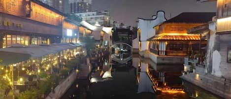 A canal with buildings on either side, a boat in the water, and lights reflecting on the surface.