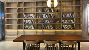 A modern interior with a wooden bookshelf filled with books, a wooden dining table with chairs, and a pendant light. - HanTing Hotel (Jiaxing Nanhu Yaohan Shopping Mall Area) (Jiaxing)