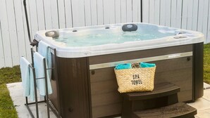 Een spabad met een houten buitenkant, een handdoekhouder en een spa-handdoekzak bevestigd aan de zijkant.