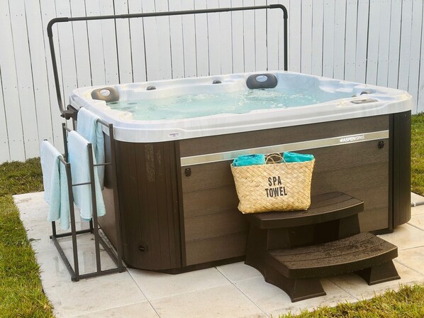 A spa hot tub with a wooden exterior, a towel rack, and a spa towel bag attached to the side. - Wilton Manors Guesthouse (Wilton Manors)