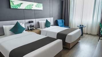 A hotel room with two beds, a small table, a chair, a painting on the wall, and a window with curtains.
