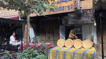 A traditional building with a signboard, a table with baskets, and a person working.