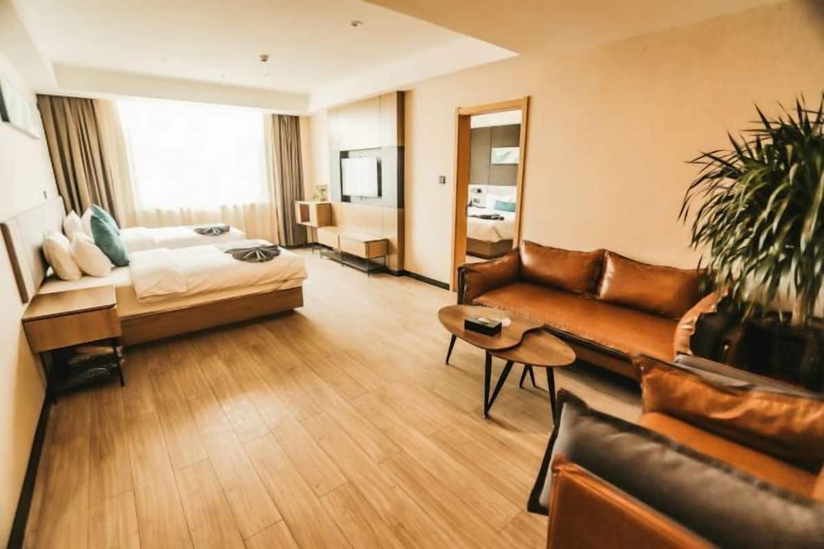 A hotel room with a bed, a sofa, a coffee table, and a large mirror.