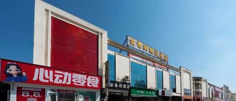 A commercial building with multiple storefronts, including a visible restaurant and a store with a blue sign.