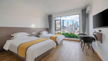 A hotel room with two beds, a TV, a city view, and a chair.