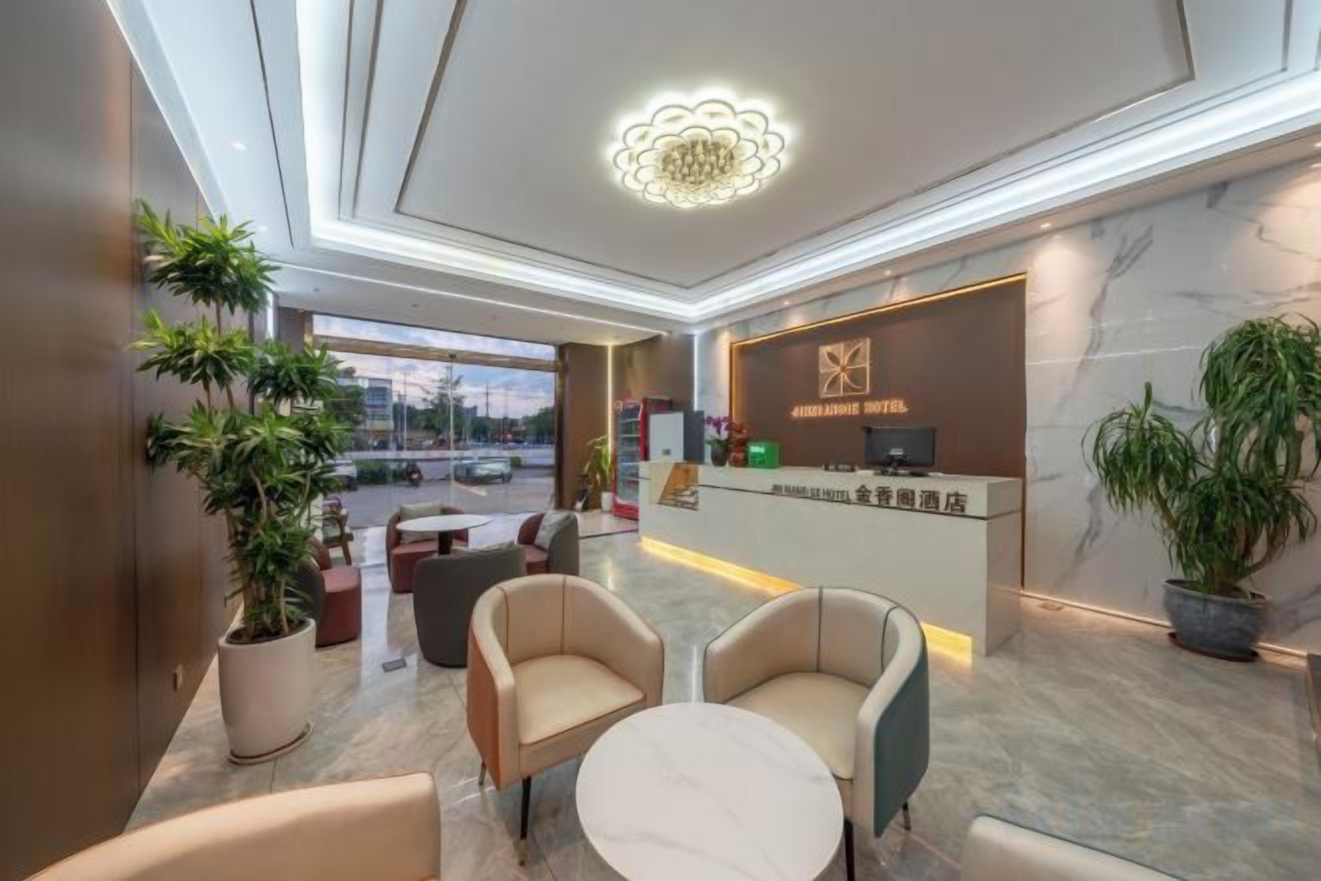 A hotel lobby with a reception desk, seating area, and large windows.