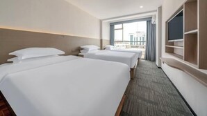 Habitación de hotel con dos camas, un televisor, una ventana con vistas y suelo alfombrado.