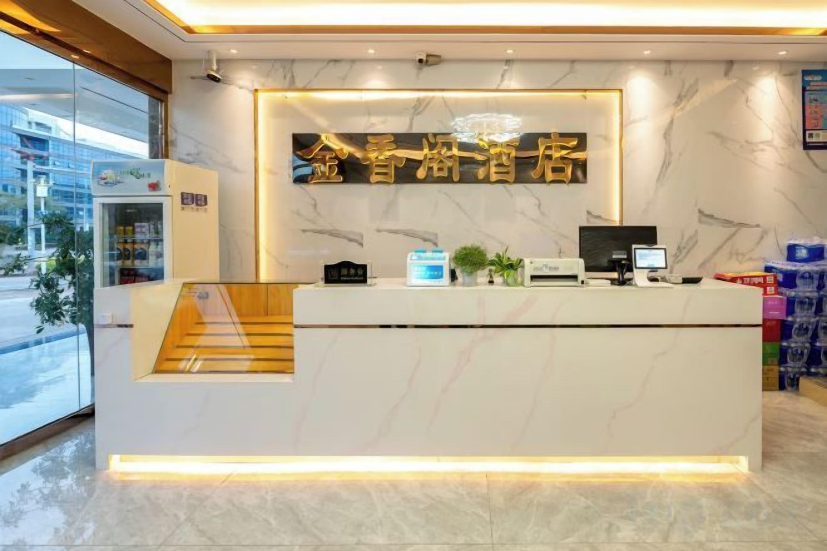 A hotel reception desk with a marble counter, a computer, and a staircase leading to an upper level.