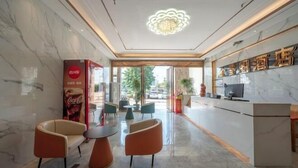 Un vestíbulo de hotel con una recepción, zona de asientos y un anuncio de Coca-Cola.