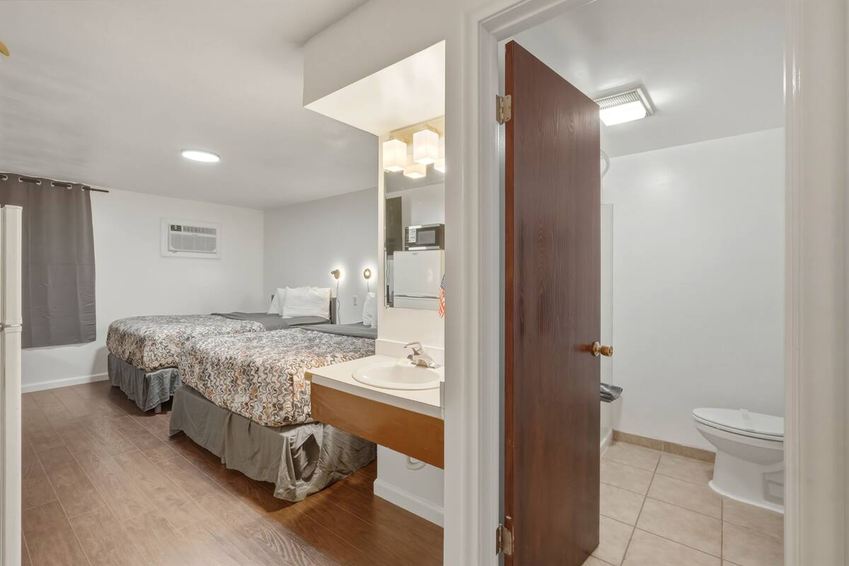 A bedroom with a bed, a vanity with a mirror, a sink, and a toilet.