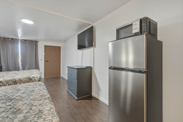 Una habitación de hotel con una cama, un escritorio pequeño, un refrigerador y un televisor fijado en la pared.