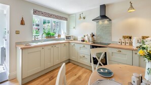 Une cuisine moderne avec des meubles blancs, une hotte noire et une fenêtre donnant sur un paysage verdoyant.