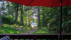 Une terrasse offrant une vue sur une zone boisée et un sentier menant à un plan d’eau.