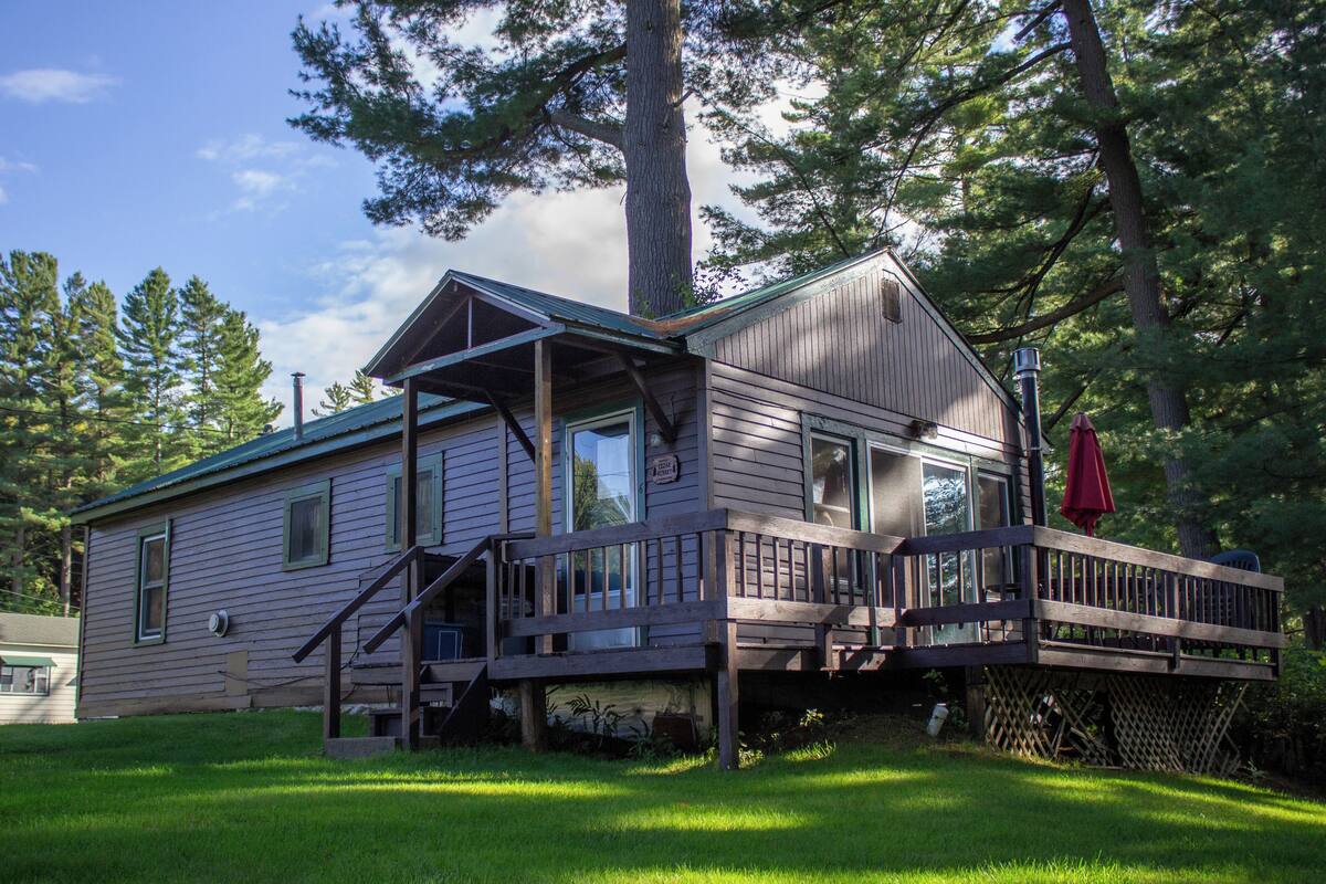 A two-story house with a deck, large windows, and a chimney.