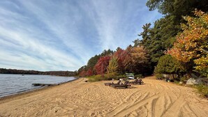 Une plage de sable bordée d’une rangée de chaises de plage et d’une rangée de tables de pique-nique.