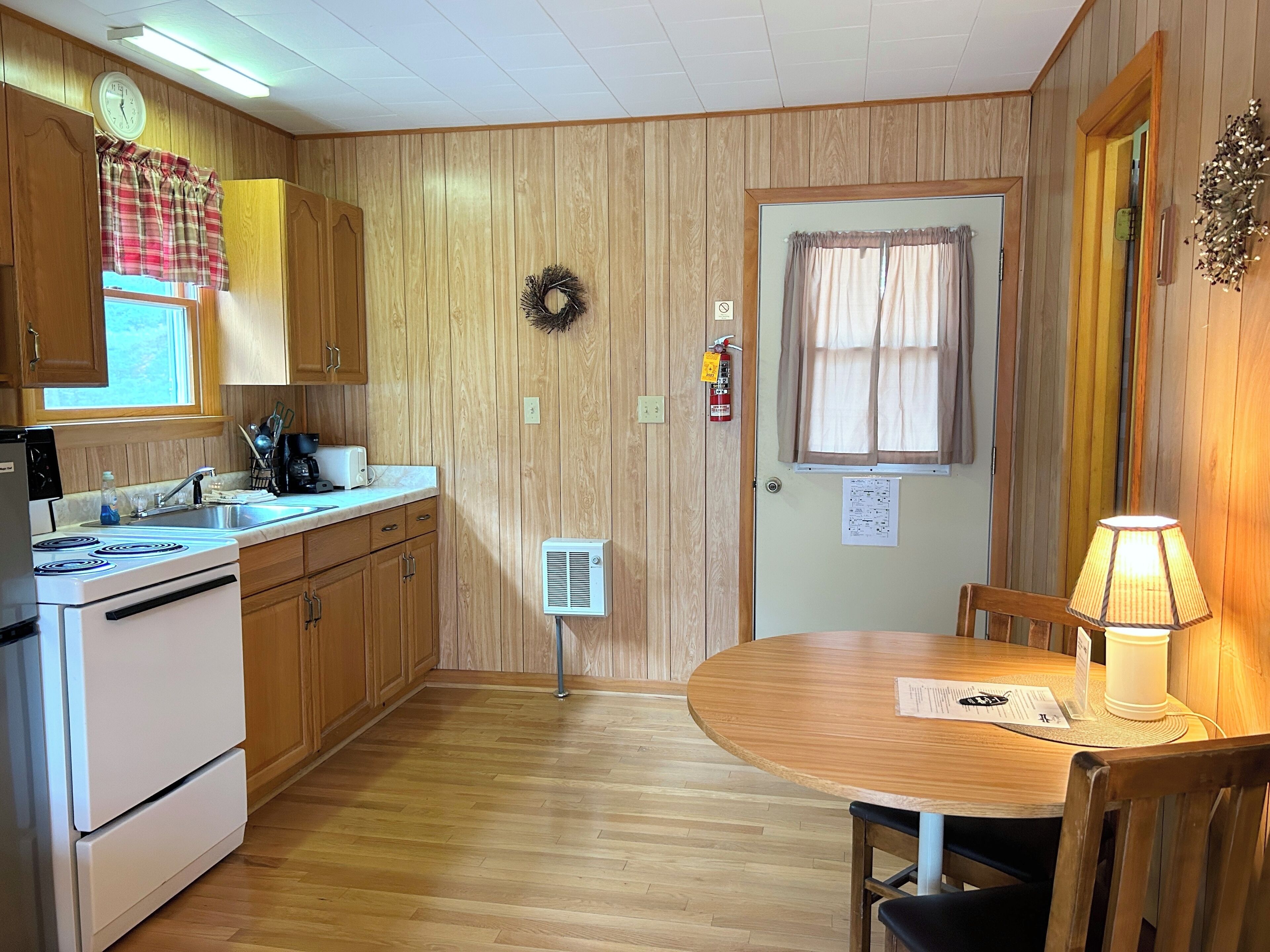 A kitchen with wooden cabinets, a stove, a sink, and a dining table with chairs.
