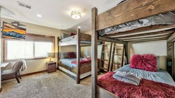 Een slaapkamer met een stapelbed, een bureau, een lamp en een schilderij aan de muur.