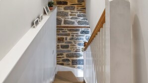 A staircase with a stone wall and wooden handrail. - 1 bedroom accommodation in Penzance (Penzance)
