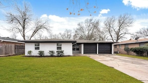 A single-story house with a garage, a small front yard, and a lawn.