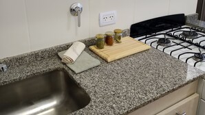 Et køkken med granitbordplader, en stålvask, en gasblus og en skærebræt med glas.