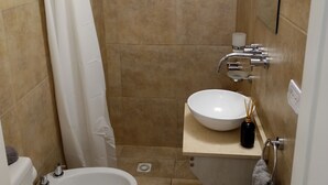 Et lille badeværelse med bruser, toilet og vask.