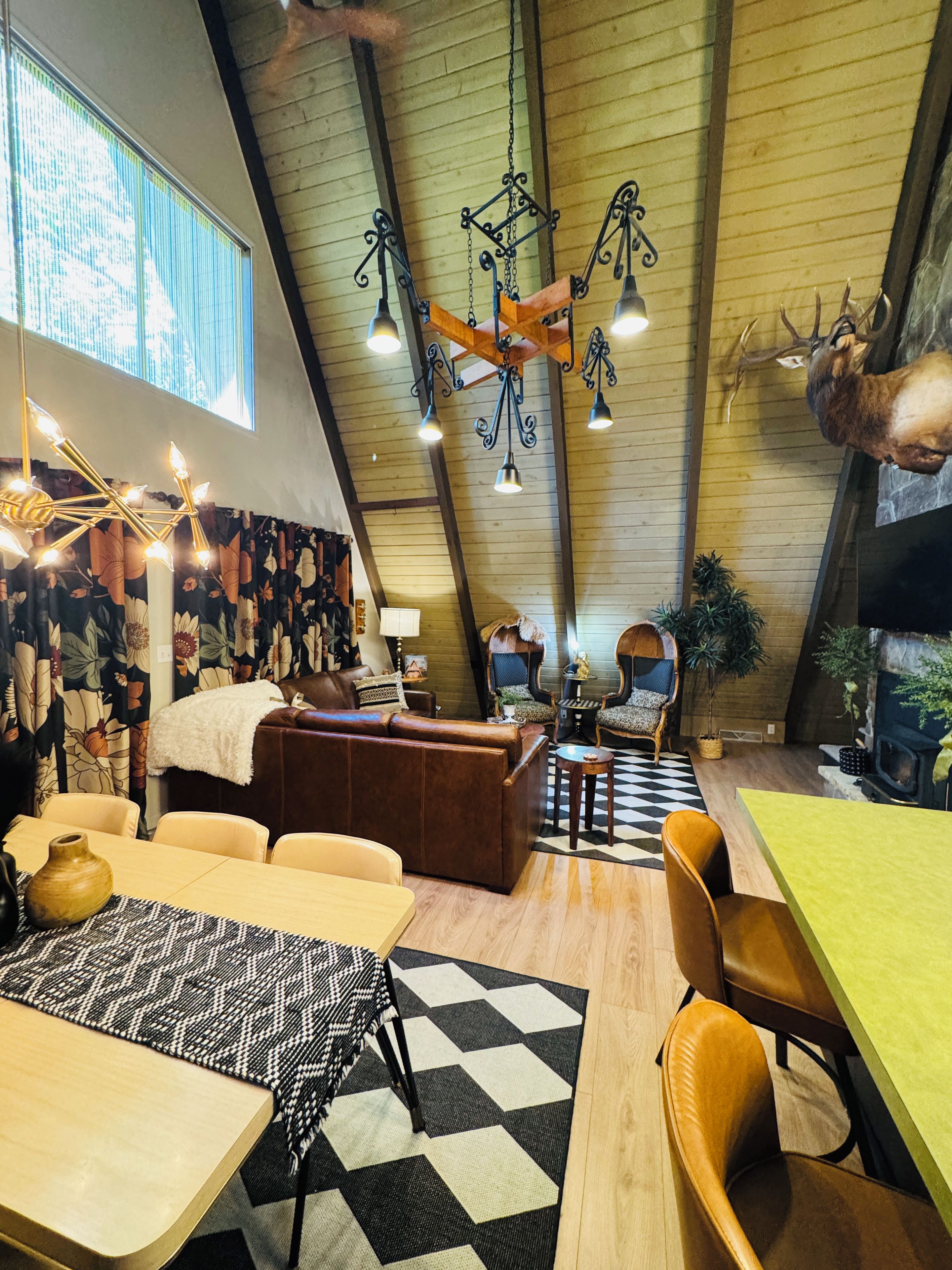 A cozy interior with a high ceiling, a fireplace, a dining area, and a seating area with a patterned rug.