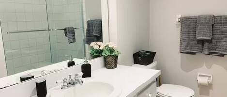 Une salle de bain moderne avec un lavabo blanc, un grand miroir, des toilettes et un porte-serviettes avec des serviettes.
