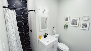 A modern bathroom with a shower, toilet, sink, and a mirror.