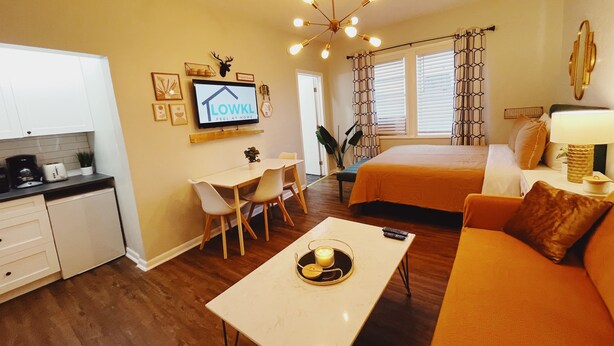 A modern living room with a sofa, a coffee table, a TV, and a dining area with a table and chairs.