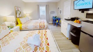 Une chambre d’hôtel avec deux lits, une kitchenette, une télévision et un coin repas.