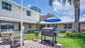 Une terrasse avec un barbecue, une table et un banc.