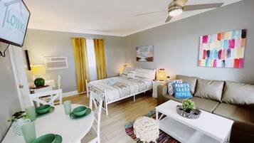 A modern, well-lit bedroom with a bed, bedside table, and a sofa.