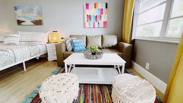 Une chambre à coucher moderne avec un lit, un canapé, une table basse et deux poufs.