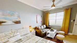 Une chambre avec deux lits, un canapé, une table basse et une fenêtre avec des rideaux.