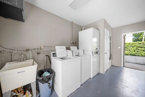 Une buanderie équipée d’un lave-linge, d’un sèche-linge et d’un évier utilitaire.