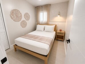 A bedroom with a bed, bedside table, wall art, and a window with curtains. - Cozy 2 Bedroom APT 1 block off the beach W/ pool (pompano beach)