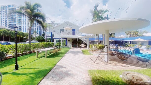 A resort with a pool area, outdoor seating, and a covered walkway. - Cozy 1 Bedroom APT 1 block off the beach W/ pool (pompano beach)