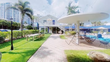 A resort with a pool area, outdoor seating, and a covered walkway.
