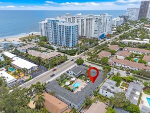 An aerial view of a coastal urban area with high-rise buildings, a beach, and a marked location. - Cozy 2 Bedroom APT 1 block off the beach W/ pool (pompano beach)