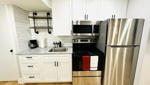 A compact kitchen with white cabinets, a stainless steel refrigerator, a microwave, and an oven. - Trendy & Central 2 Bedroom Apt (Fort Lauderdale)