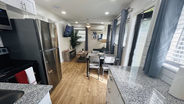 A modern kitchen with granite countertops, stainless steel appliances, and wooden flooring. - Stylish & Convenient 2 BR Apt (Fort Lauderdale)