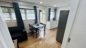 A compact kitchen with white cabinets, a black refrigerator, and a window with a curtain. - Stylish & Convenient 2 BR Apt (Fort Lauderdale)