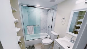 Une salle de bain avec une douche à parois de verre, des toilettes, un lavabo et un miroir.