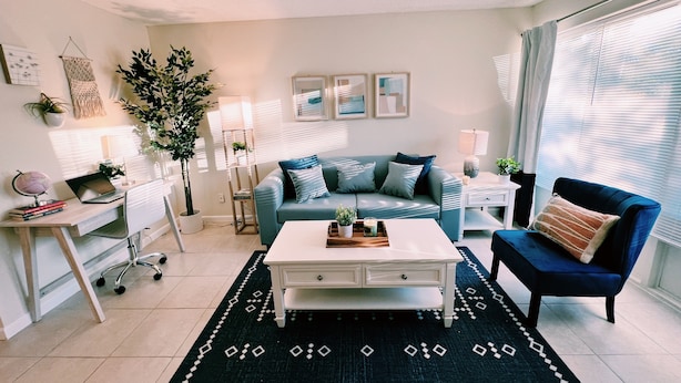 Uma sala de estar moderna com um sofá, mesa de centro e escrivaninha com um laptop.