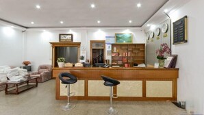 A reception area with a wooden counter, two black bar stools, a reception desk, a wall-mounted clock, and a framed picture. - Xianju Stomping Songs Homestay (Xianju)