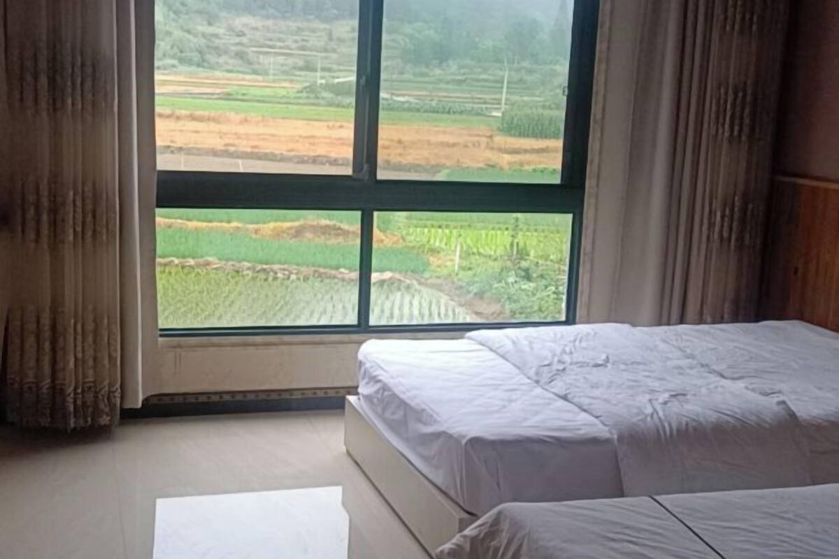 Un dormitorio con una ventana grande, una cama y cortinas.