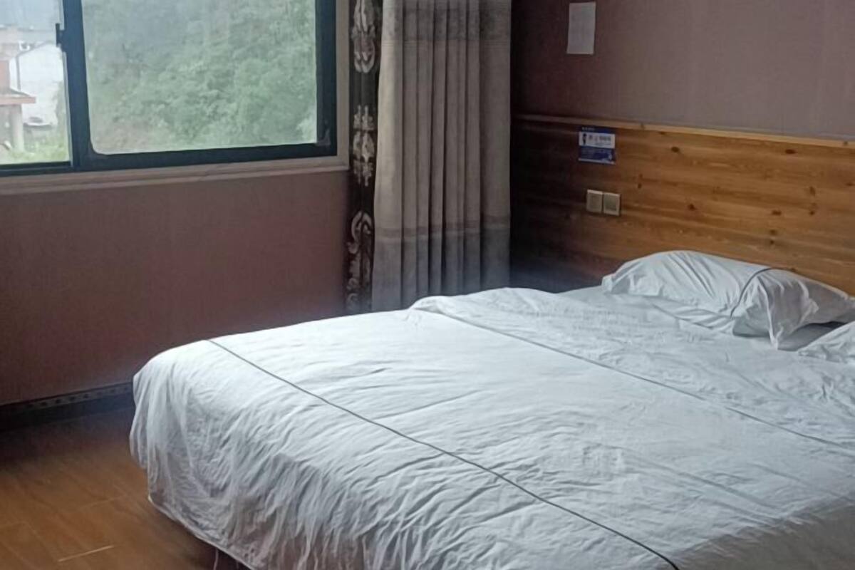 Una habitación con cama, ventana y cabecera de madera.